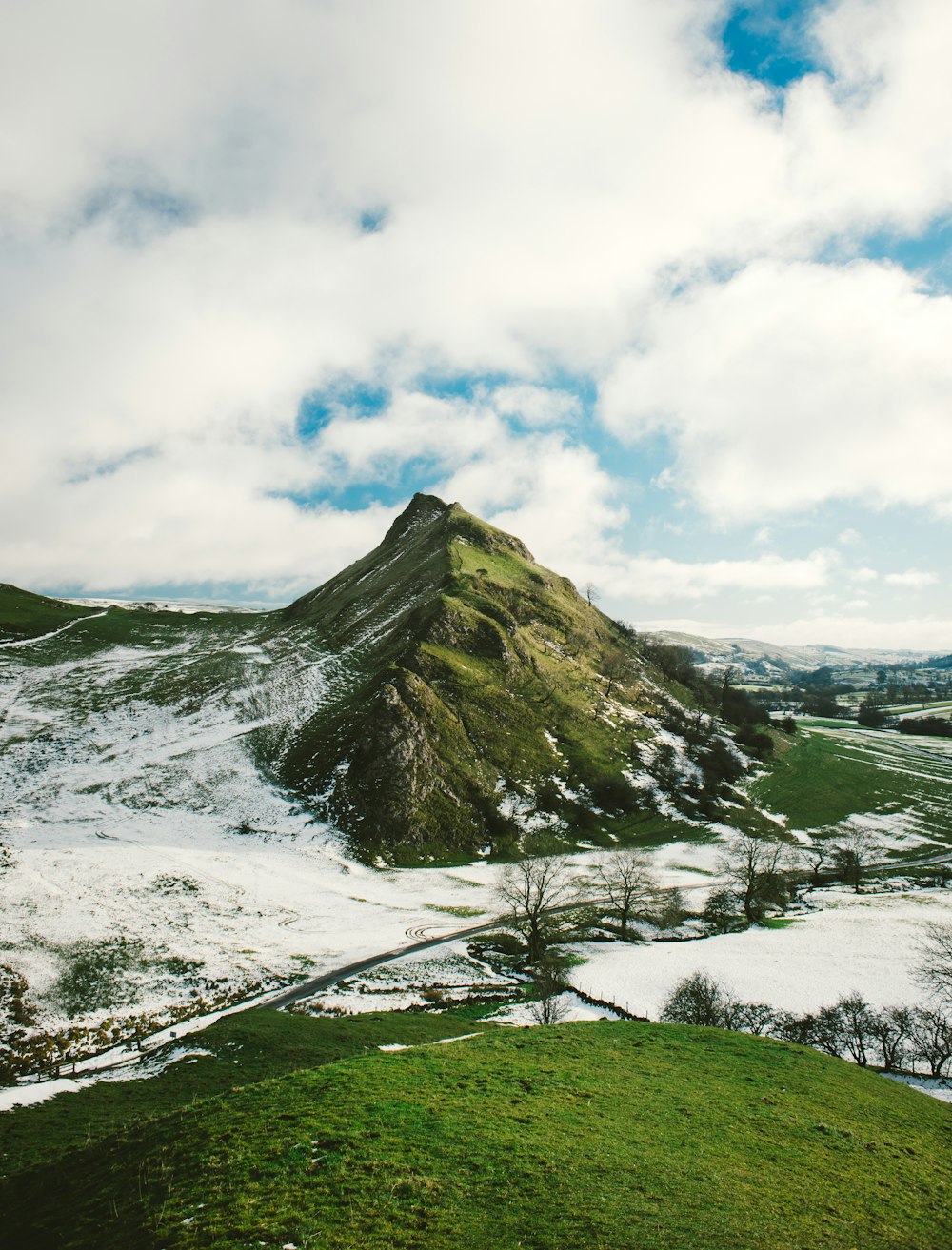 snowy hill under white clouds at daytime