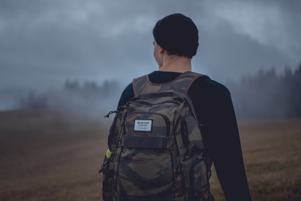 man carrying gray camouflage backpack