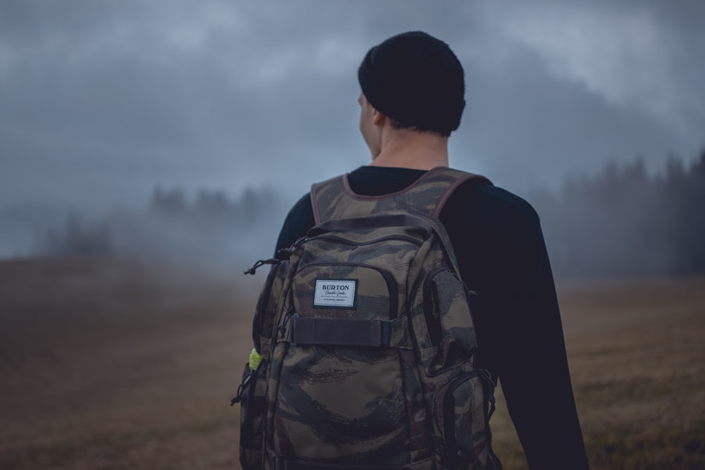 homme portant un sac à dos camouflage gris