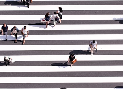 aerial view photography of group of people walking on gray and white pedestrian lane