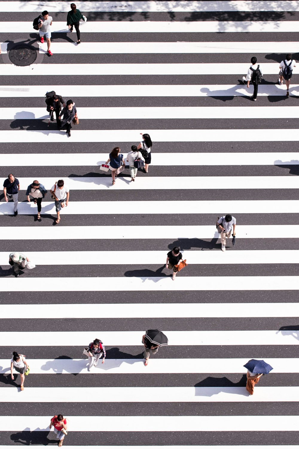 Luftbildfotografie einer Gruppe von Menschen, die auf einer grau-weißen Fußgängerzone spazieren gehen