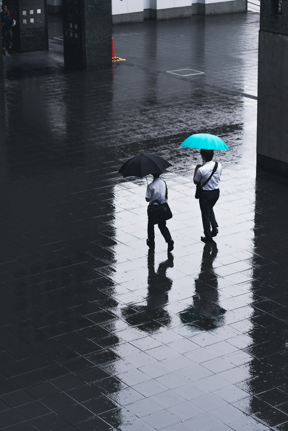 Due uomini che camminano sulla strada con ombrelli in mano durante il tempo piovoso