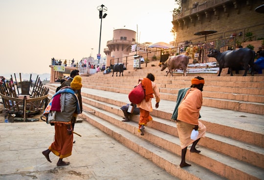 person holding white plastic bottles walking on gray concrete stairs in Varanasi India