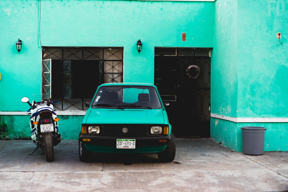 green Volkswagen car beside concrete building