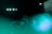 A person is singing or speaking into a microphone on a stage with musical equipment. The scene is illuminated by teal and green lights, creating a moody atmosphere. A portion of a screen displaying text is visible in the background.
