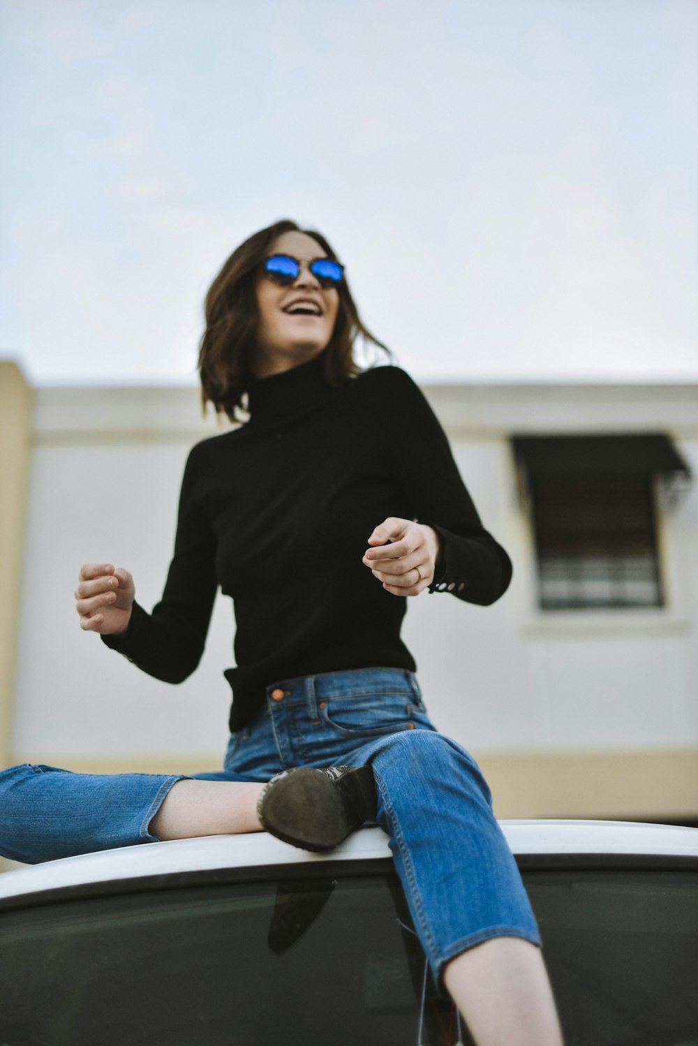 woman wearing black high-neck long-sleeved top while sitting on top of vehicle