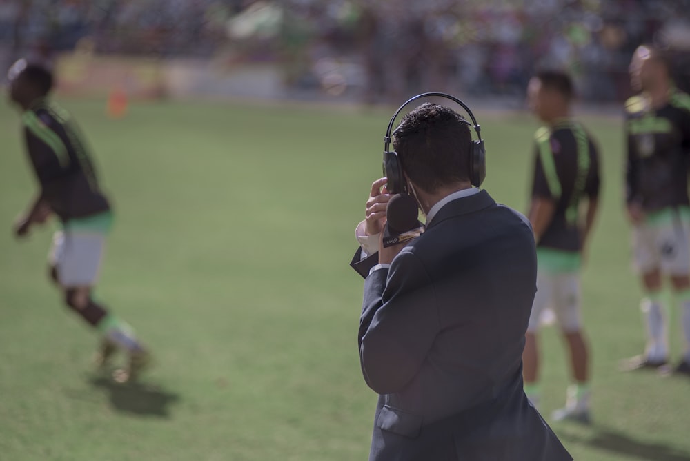 Fotografía de enfoque selectivo de hombre usando auriculares cerca de atletas