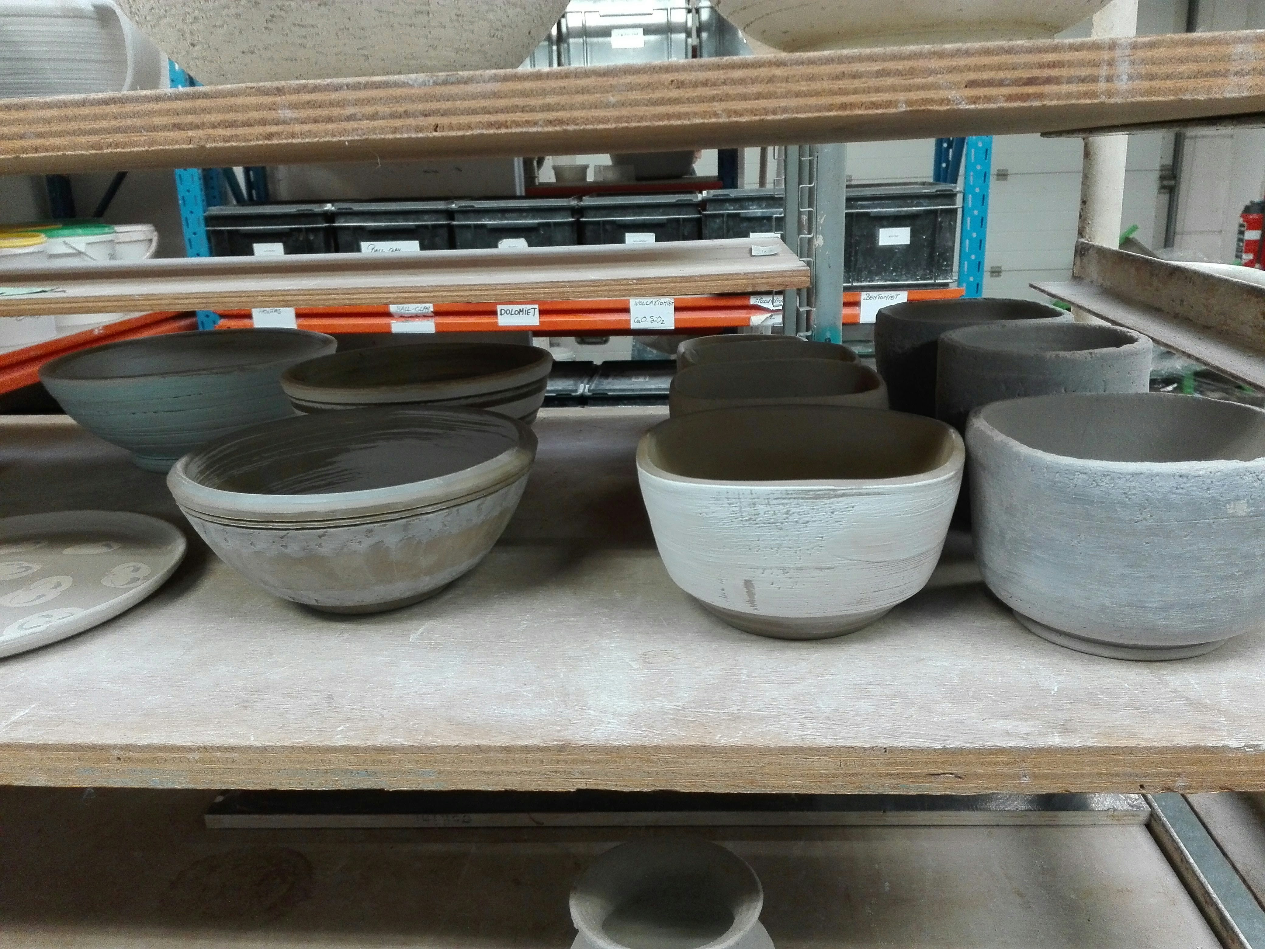 Finished handmade ceramic mugs and plates arranged neatly on a studio table for inspection
