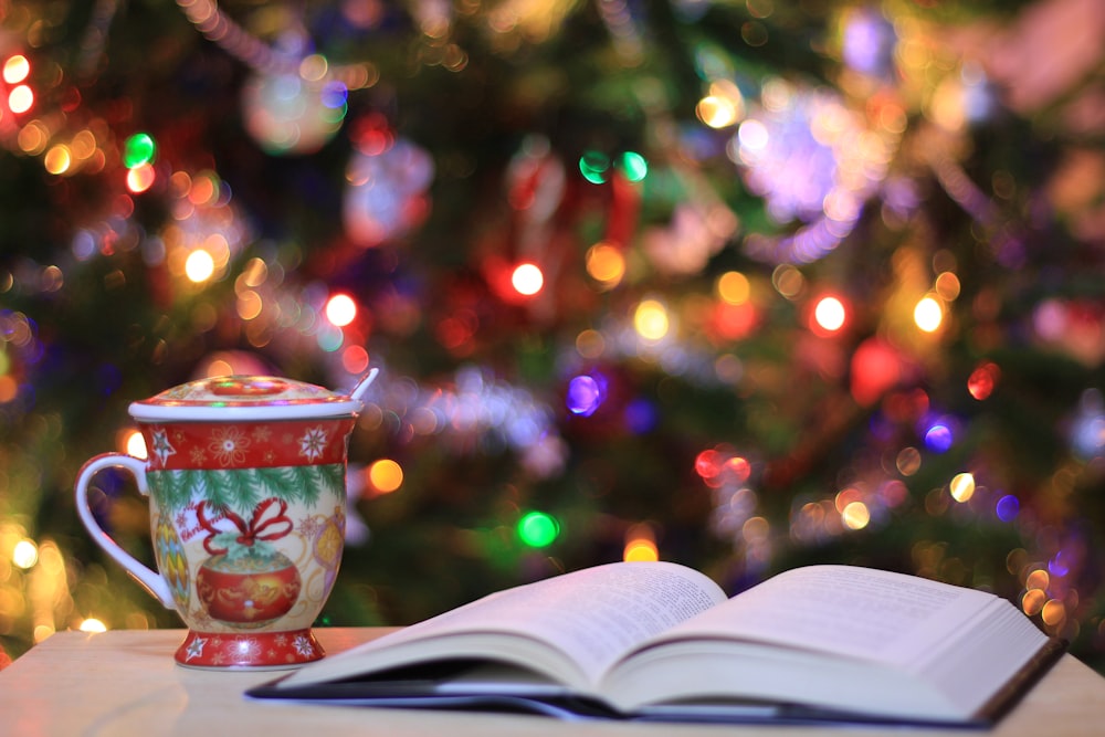 red and green ceramic mug beside book