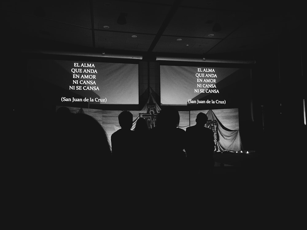 grayscale photography of people standing in front of board