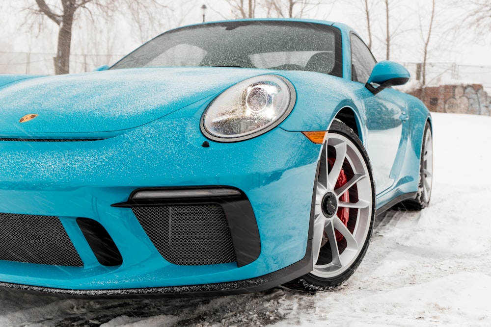 Porsche Cayman azul en un campo de nieve cerca de los árboles