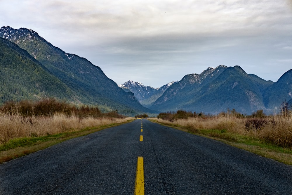 road near mountains under gray sky