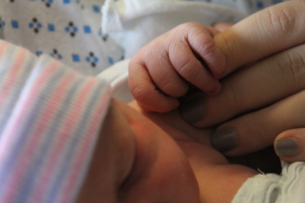 A close-up of tiny baby hands grasping a parent's finger.