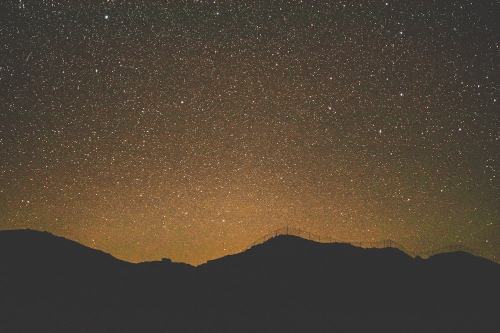 silhouette of mountain under starry night sky