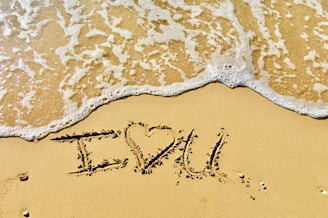 aerial photo of I love you text on sand at the seashore