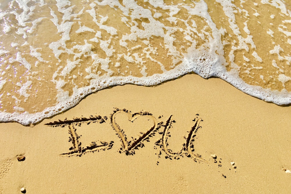 aerial photo of I love you text on sand at the seashore