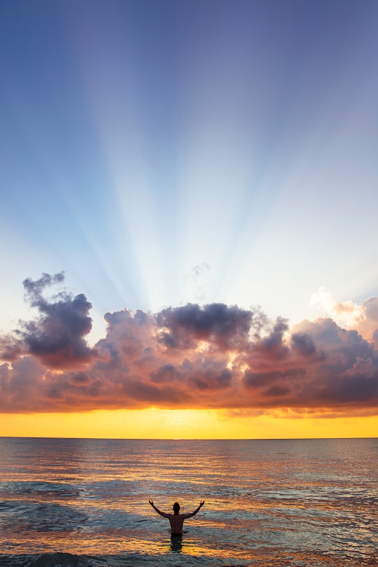 man raising his arms on sea under black clouds in South Beach United States