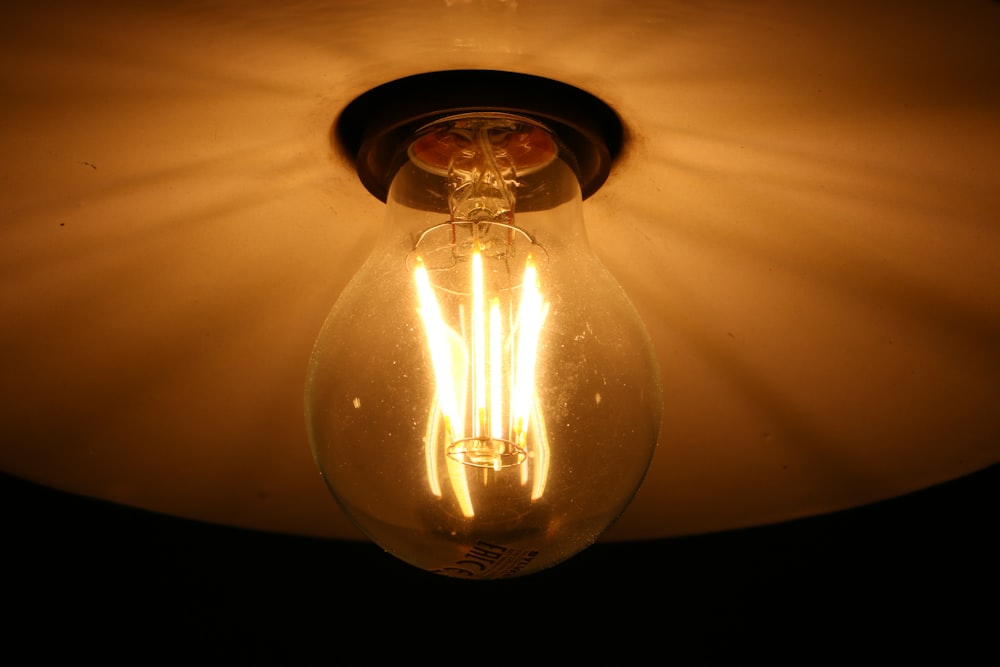clear glass light bulb turned on on white textile