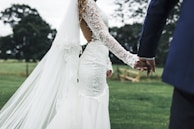 A couple holding hands in front of a scenic outdoor wedding venue.