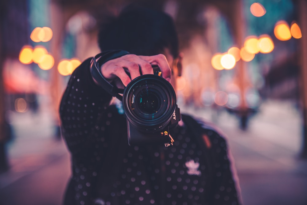 man holding black DSLR camera