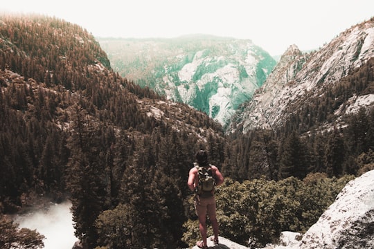 man standing on cliff while holding his backpack in Yosemite Valley United States