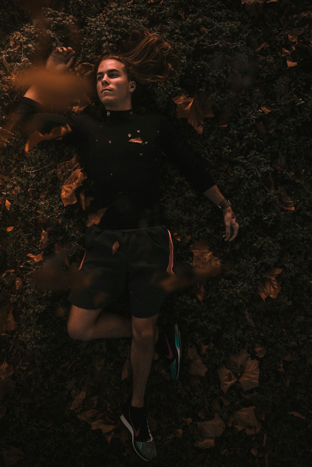 a man laying on the ground surrounded by leaves