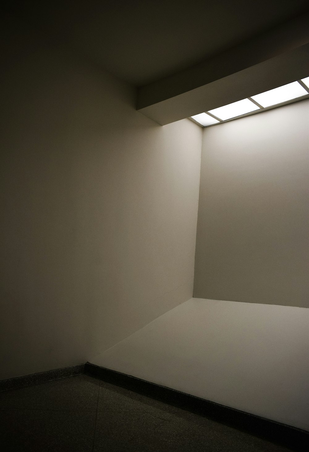 an empty room with a light coming from the ceiling