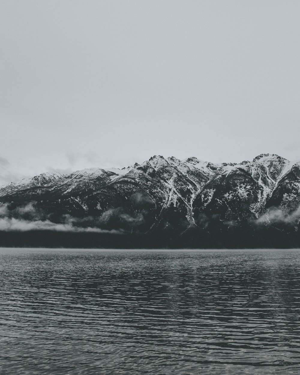 grayscale photo of mountain near body of water