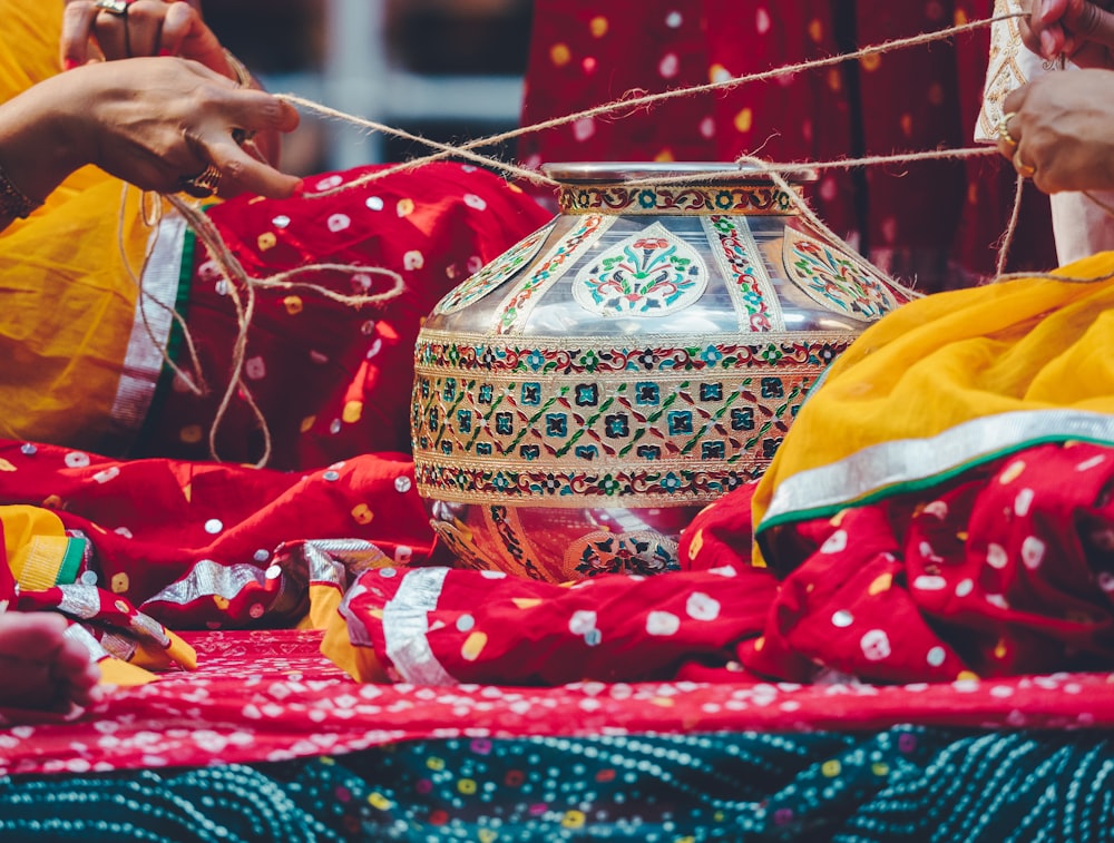 photo of two person tying brown and green floral pot using rope