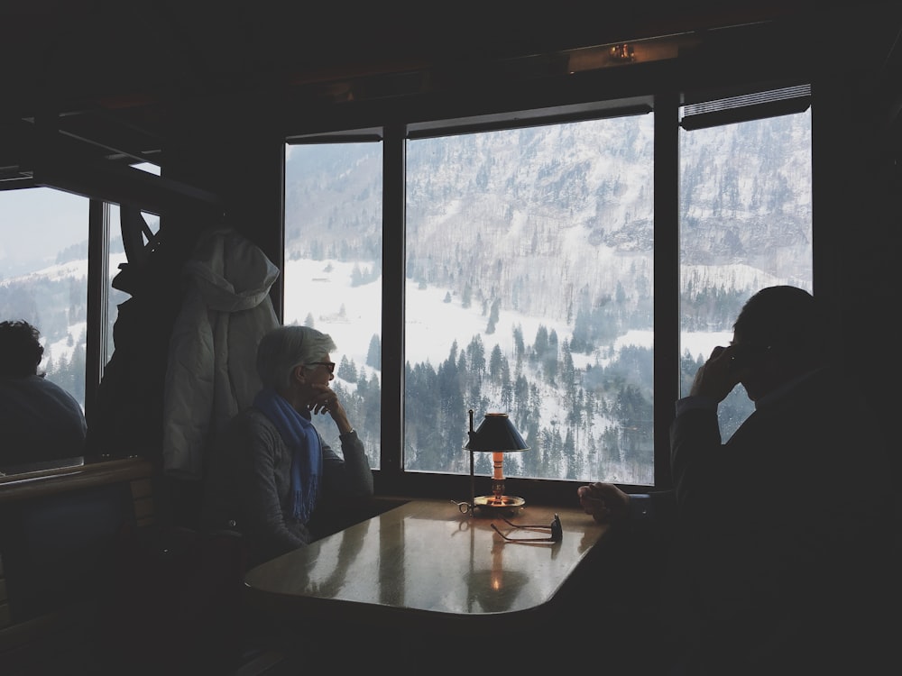 zwei Personen sitzen am Tisch und beobachten den schneebedeckten Hügel
