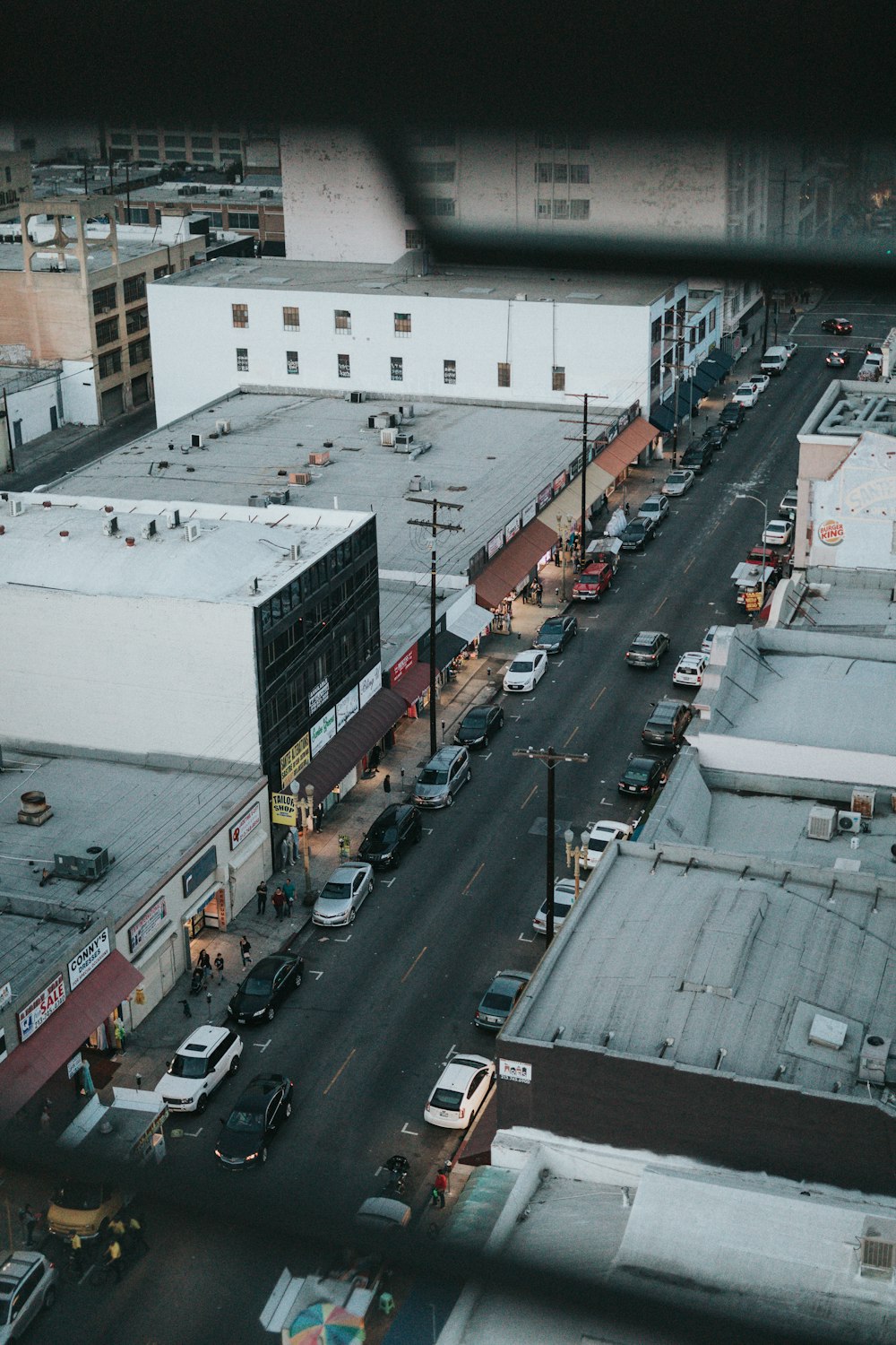 gray asphalt road between of car parking on sidewalks during daytime