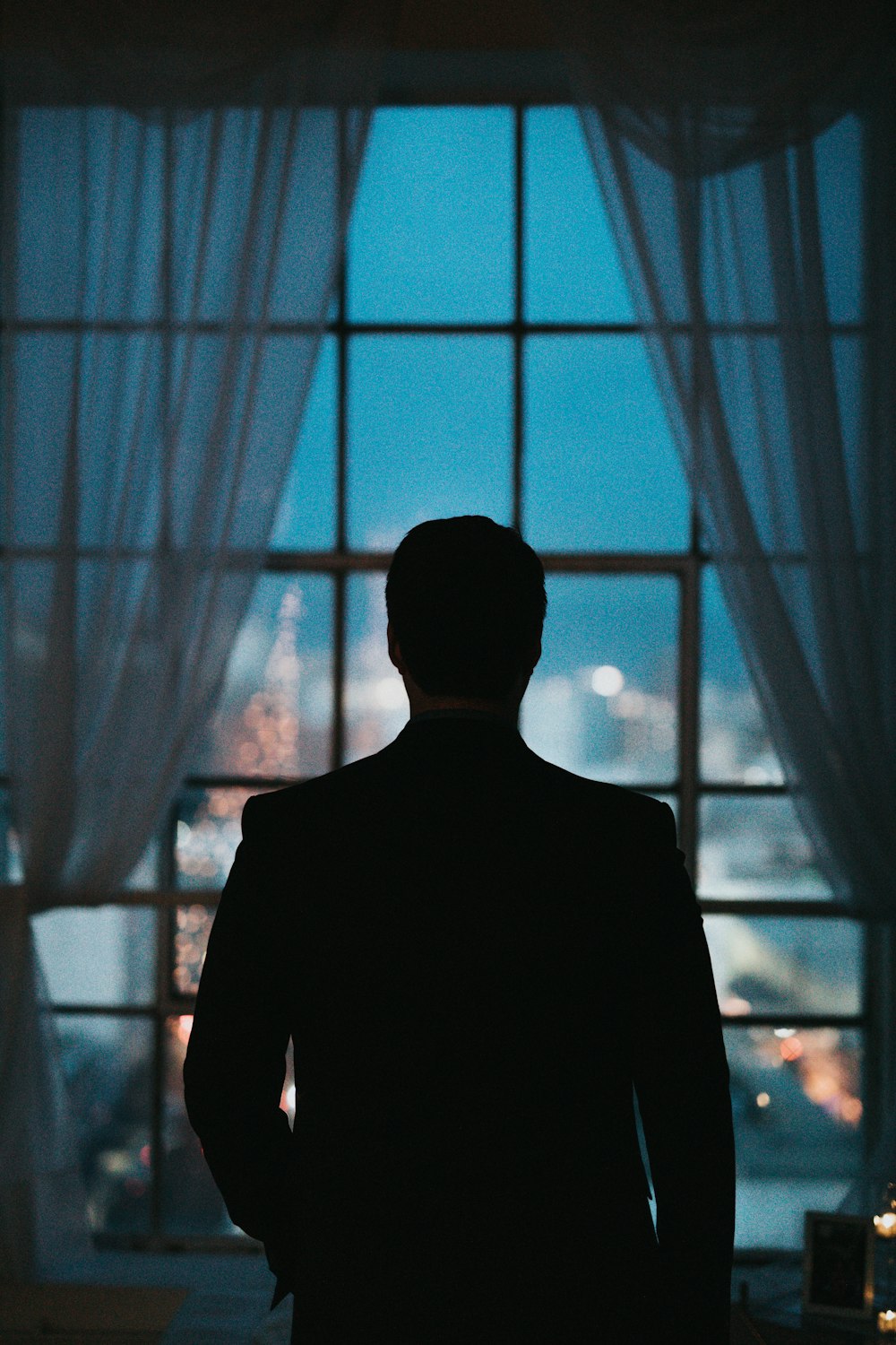 silhouette of person standing against windowpane