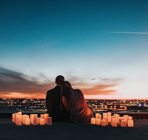 couple sitting on the field facing the city