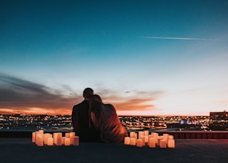 couple sitting on the field facing the city