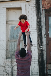 A caring mentor and a young child sharing a joyful moment outdoors in an urban neighborhood.