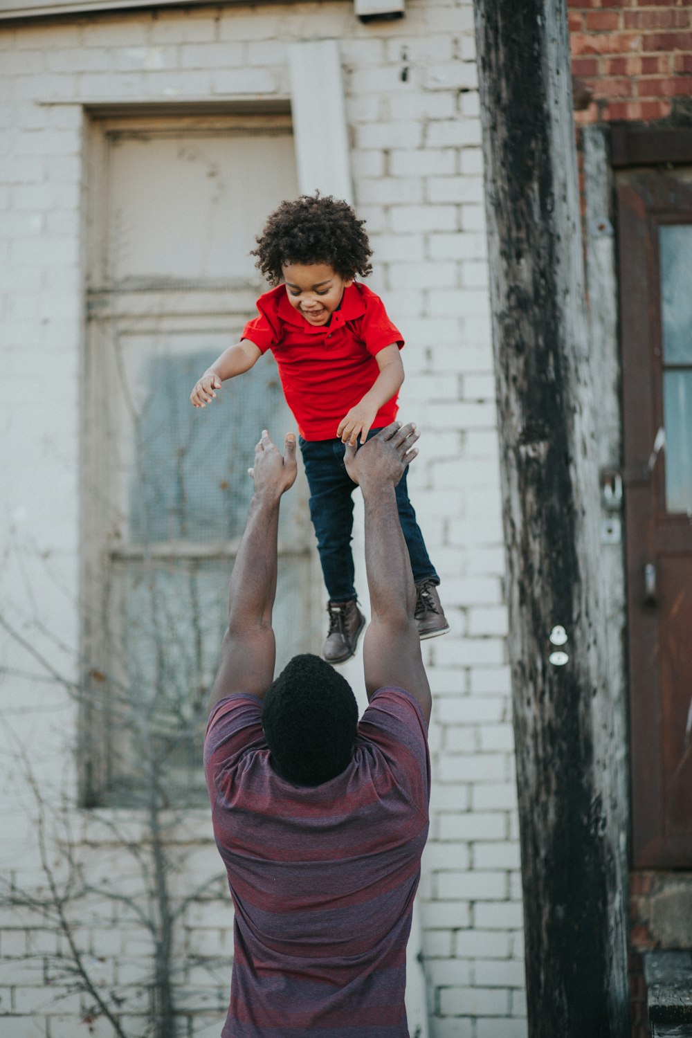 man wearing purple and red shirt catching child wearing red shirt