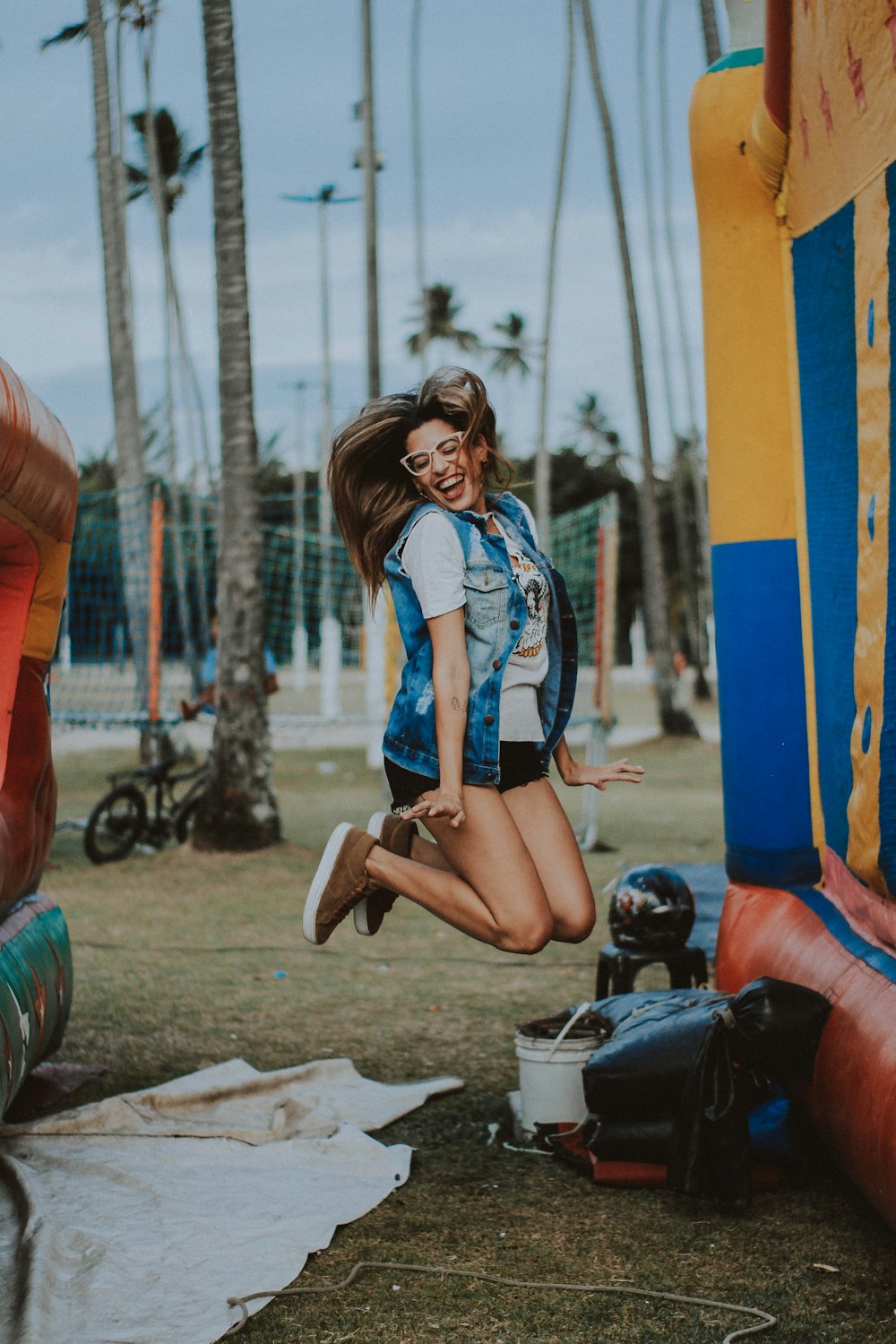 a woman jumping in the air near a bouncy castle