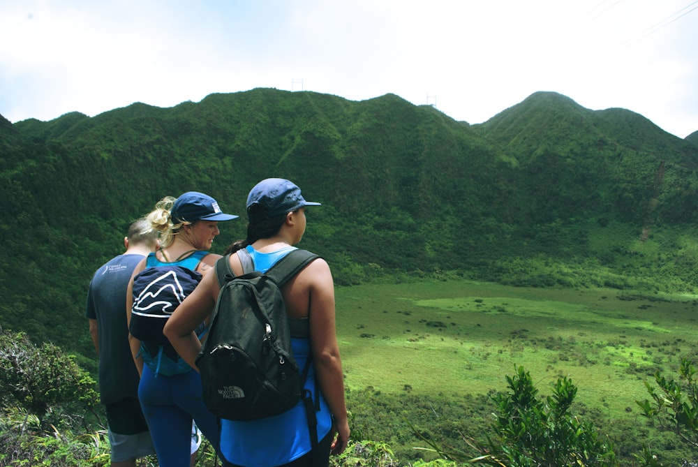 tres mujeres de pie con una vista de la montaña verde bajo el cielo gris