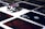 A stack of poker chips with a distinctive black and white pattern is placed on a table covered with several playing cards. The cards are dark with red and white symbols, creating a bold contrast against the lighter surface.