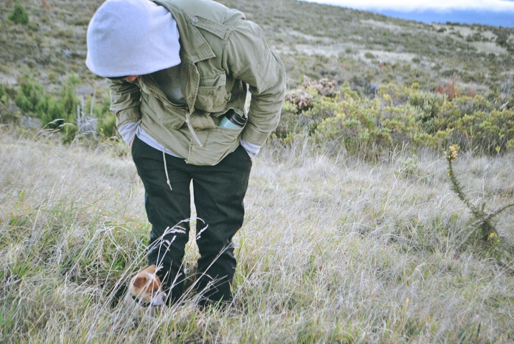 person looking down on puppy on field