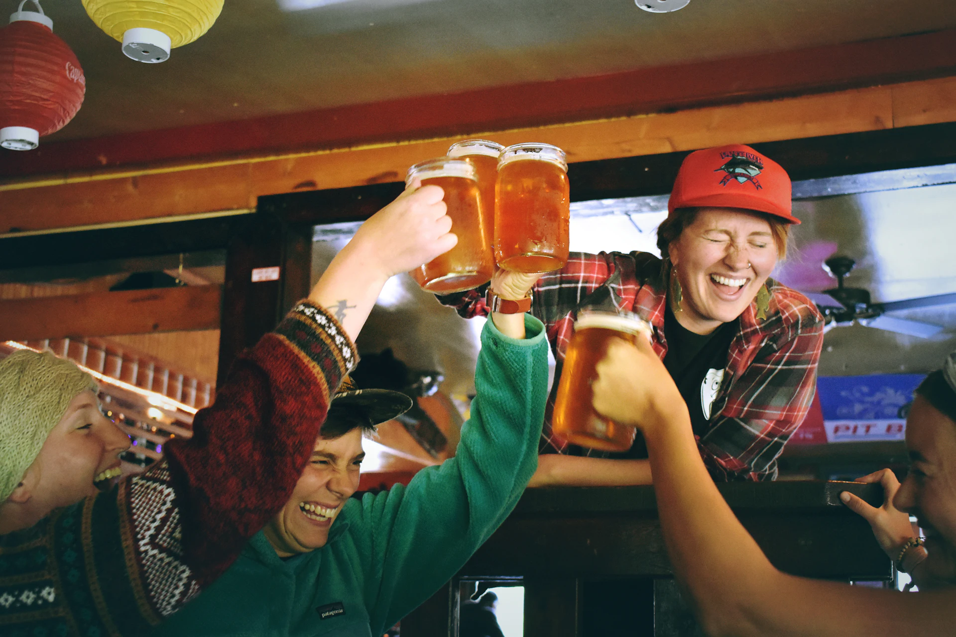 Friends raising full pints in the taproom