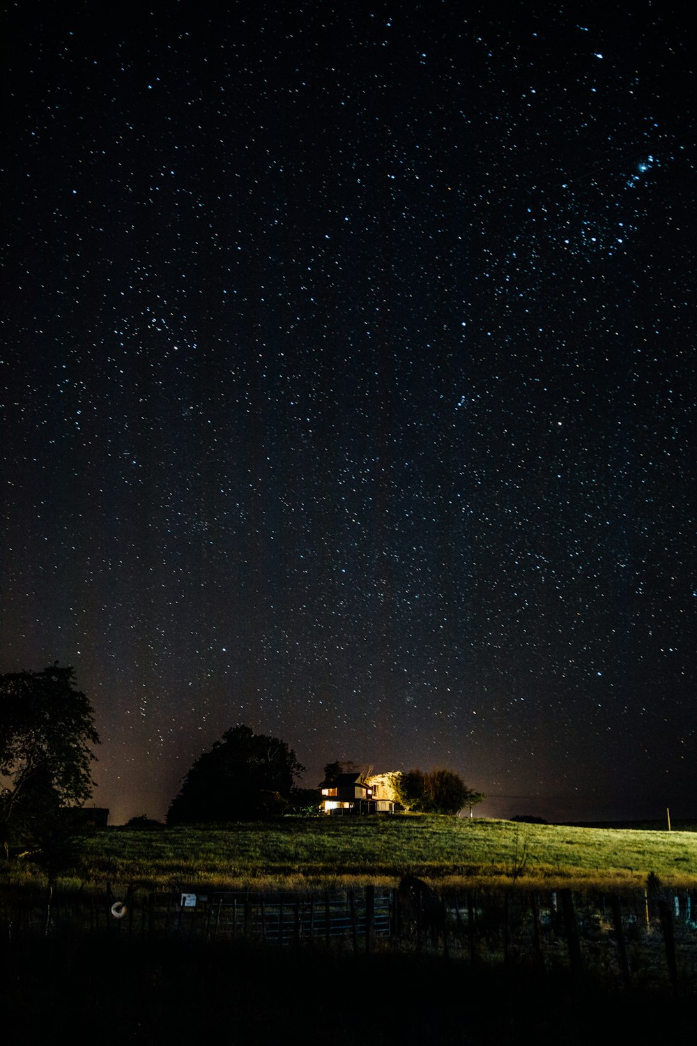 brown wooden house near body of water under starry night