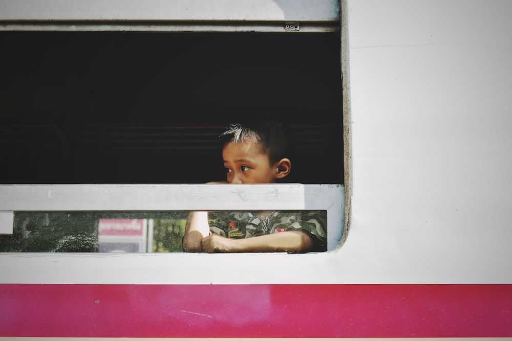Junge in der Nähe des Fahrzeugfensters während der Tagesfotografie