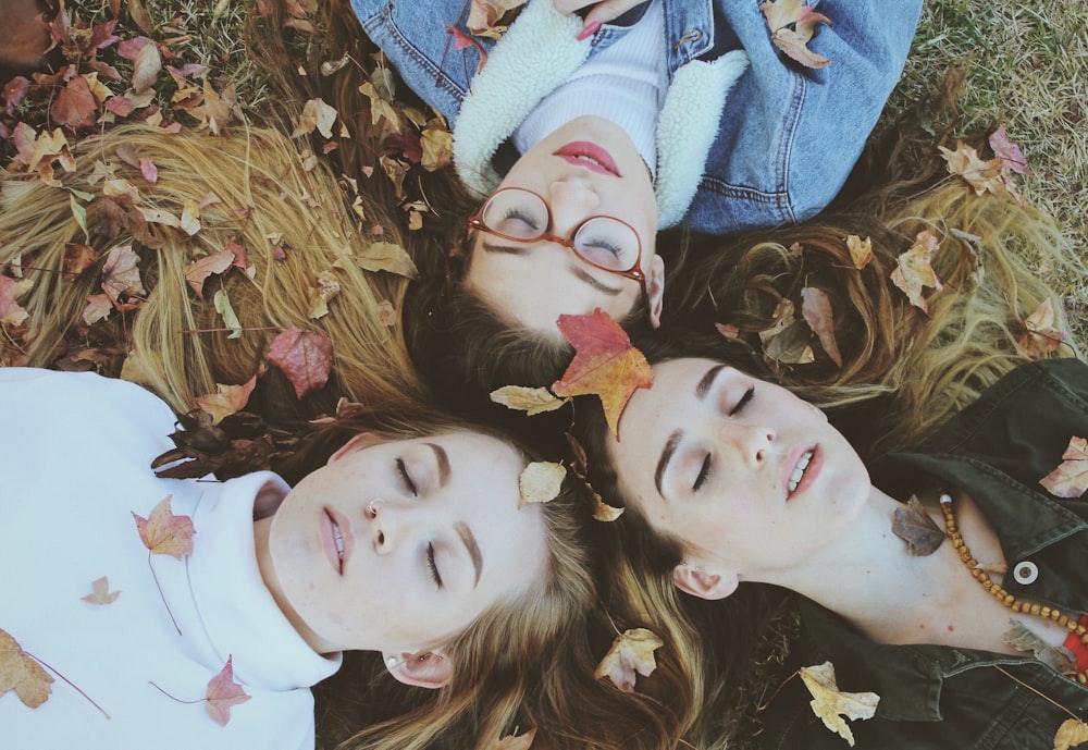 three women laying on green grass