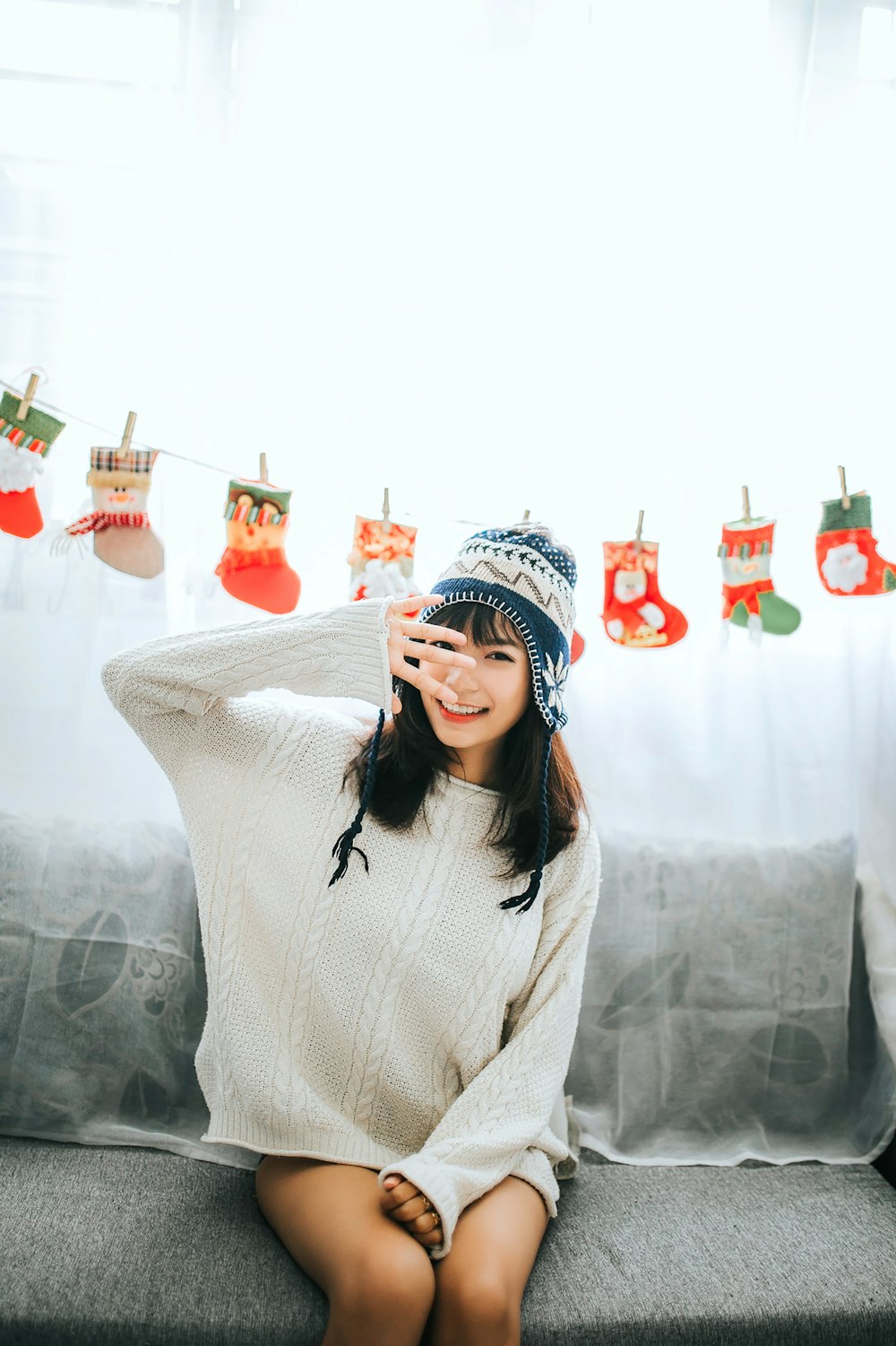 woman wearing white sweater sits on gray fabric sofa