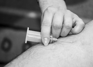 grayscale photo of person holding syringe