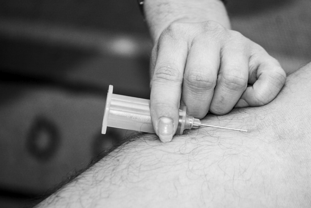 grayscale photo of person holding syringe