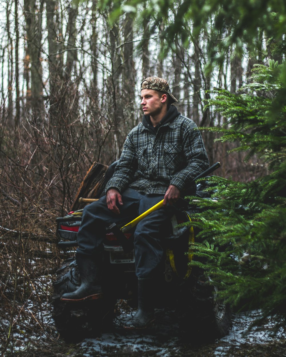 man sitting on yellow all-terrain vehicle in forest