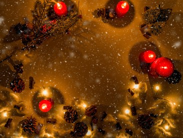 A festive arrangement with red candles surrounded by pine cones, cinnamon sticks, and delicate, warm string lights. A gentle snow effect overlays the scene, adding a wintry atmosphere.