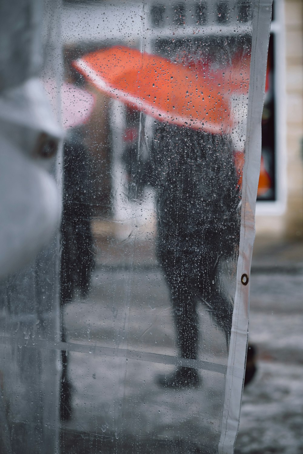 clear plastic coat with water drops showing people using umbrella